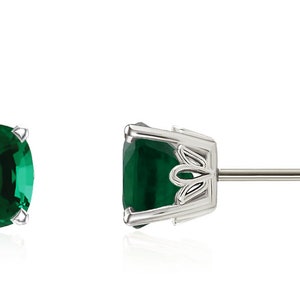 May include: A pair of emerald green gemstone earrings with a silver setting and post back.