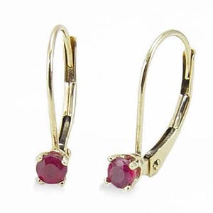 May include: A pair of gold hoop earrings with a small round red ruby gemstone in each earring.