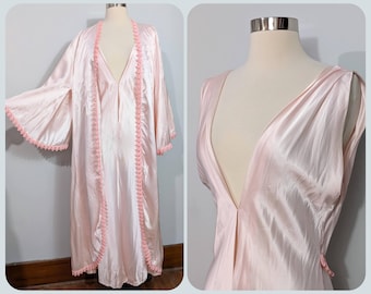 May include: A light pink satin robe and matching slip dress. The robe has wide sleeves and is trimmed with pink lace. The slip dress has a deep V-neckline. Both garments are displayed on a mannequin.
