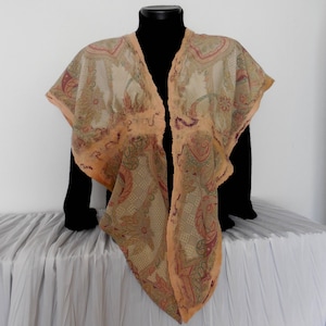Puede incluir: Un chal transparente de frente abierto con un estampado floral y paisley en tonos melocotón, verde y burdeos. El chal está drapeado sobre una forma negra, mostrando su diseño fluido y detalles intrincados. Los bordes están ribeteados con un borde color melocotón.