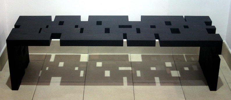 May include: A black wooden bench with a unique geometric design featuring cut-out squares. The bench has a modern and minimalist aesthetic.