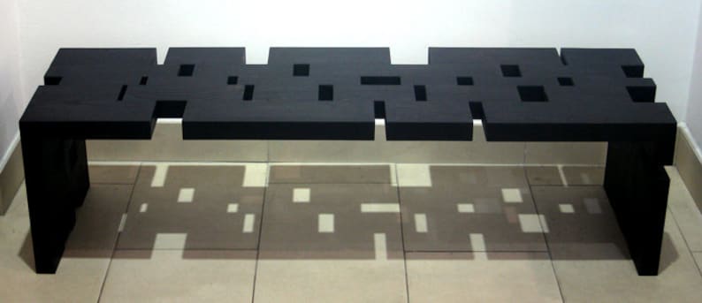 May include: A black wooden bench with a unique, geometric design. The bench has a series of cutouts in the top surface, creating a pattern of squares and rectangles.