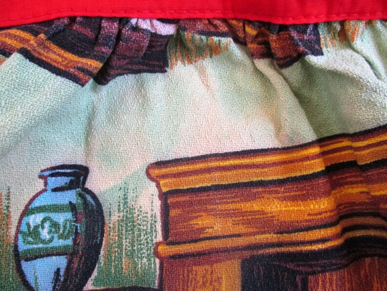 Puede incluir: Primer plano de una tela vintage con un dise&ntilde;o del suroeste. La tela presenta un jarr&oacute;n de cer&aacute;mica azul y verde, una chimenea de madera y un fondo estampado verde y marr&oacute;n.