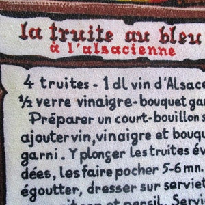 Puede incluir: Una tarjeta de receta vintage con fondo blanco y texto negro. La receta es para "la truite au bleu &agrave; l'alsacienne", que se traduce como "trucha azul al estilo alsaciano". La receta requiere 4 truchas, 1 decilitro de vino de Alsacia, 1 1/2 vasos de vinagre, un bouquet garni y sal. Las instrucciones son preparar un caldo corto, agregar el vino, el vinagre y el bouquet garni, pochar las truchas durante 5-6 minutos, escurrir y servir.