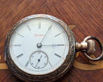 Raro y ornamentado Dueber Hampden de 1891, tamaño 18, movimiento damasquinado con 15 joyas que funciona y mantiene la hora