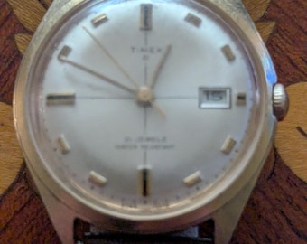 Reloj de pulsera Timex Prestige vintage de 1969 con esfera color champán y cruz, 21 rubíes, cuerda manual, funcionando y manteniendo la hora.