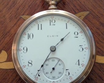 Reloj de bolsillo Elgin de 1907, tamaño 18, con 7 joyas y caja de fibra de vidrio ornamentada, en estado excepcional. Funciona y mantiene la hora correctamente.
