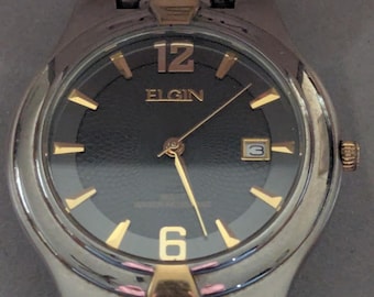 Reloj de pulsera vintage Elgin Quartz para hombre, de acero inoxidable en tonos plateados y dorados, en su caja y documentación originales. Funciona y mantiene la hora correctamente.