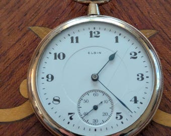Reloj de bolsillo Elgin de 1921, tamaño 16, chapado en oro, con caja ornamentada. 17 rubíes que marcan la hora.