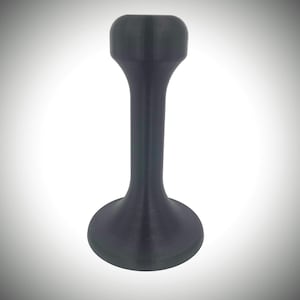 Könnte beinhalten: Ein schwarzer Gummiklappenstopper mit abgerundeter Oberseite und breiter Basis.