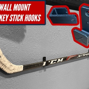 May include: Wall mounted hockey stick hooks made of blue plastic. The hooks are designed to hold hockey sticks in place. A hockey stick is hanging on the hooks. The stick is black with a white blade and the text "JETSPEED" and "CCM" printed on it.