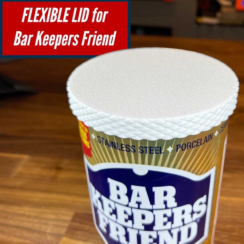 May include: A white plastic lid with a rope-like design around the edge. The lid is on top of a yellow and blue can that says "Bar Keepers Friend" and "Stainless Steel, Porcelain".