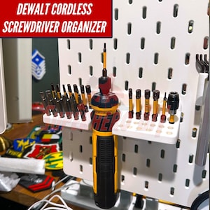 May include: A yellow and black cordless screwdriver with various bits organized on a white pegboard. The text "DEWALT CORDLESS SCREWDRIVER ORGANIZER" is displayed in a red box at the top. The screwdriver and bits are the primary focus.
