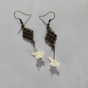 May include: A pair of earrings with a bronze-colored, intricate knot design and a white bone-like pendant.