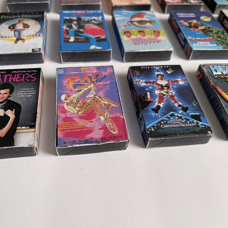 May include: A collection of VHS tapes featuring various movie titles, including "Field of Dreams", "The Christmas Vacation", "Rad", and "Heathers".