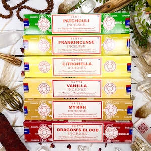 May include: A stack of six incense sticks with different scents, including Patchouli, Frankincense, Citronella, Vanilla, Myrrh, and Dragon's Blood. Each stick is labelled with the scent and the brand name "Satya" in red and white text. The sticks are packaged in colourful boxes with a gold "Export Quality" label.