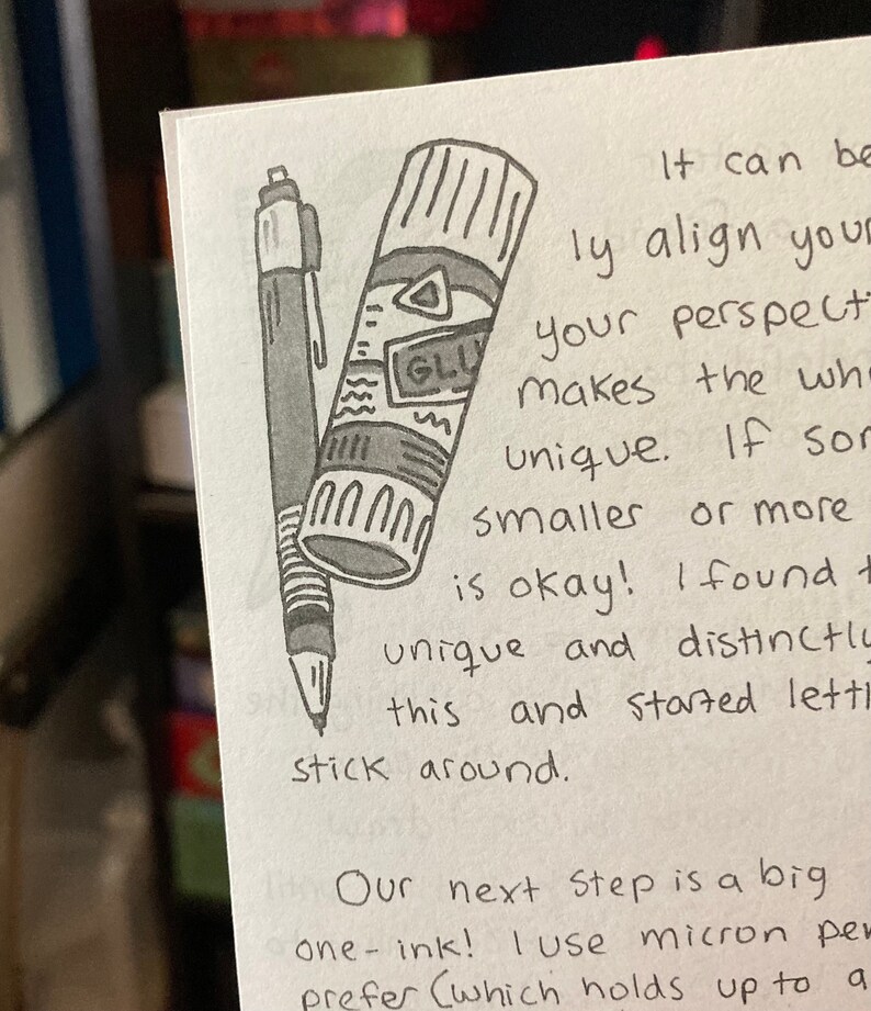 May include: A hand-drawn illustration of a glue stick and a pen. The glue stick is labeled "GLU" and has a white cap. The text reads "It can be easily align your perspective makes the whole unique. If something smaller or more is okay! I found this and started letting it stick around. Our next step is a big one-ink! I use micron pens (which holds up to a"
