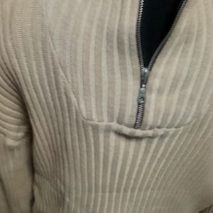 May include: A beige ribbed jumper with a zip up the front. The zip is silver and has a black lining.