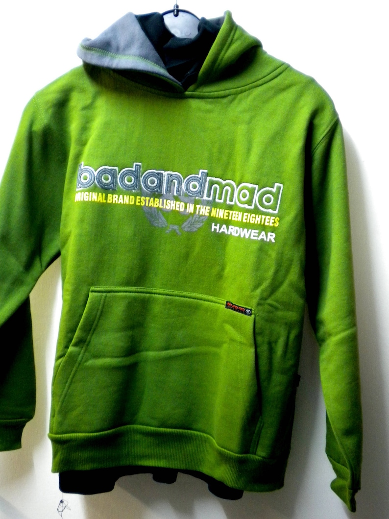 May include: Green hooded sweatshirt with the text "badandmad" in white and yellow lettering. The text "Original Brand Established in the Nineteen Eighties" is in white lettering below the logo. The text "Hardwear" is in white lettering below the text.