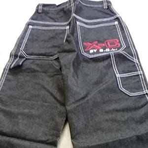 May include: Black denim jeans with white stitching and a red embroidered logo that says "X-C BY S.D."