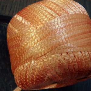 Puede incluir: Una bola de hilo naranja y blanco con textura tejida.