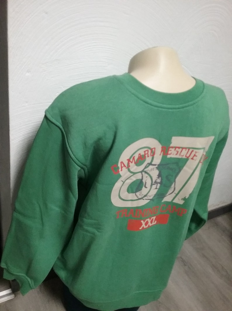 May include: Green sweatshirt with a white and red graphic print that says "Camard Rescue 87 Training Camp XXL".