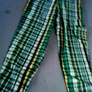 Könnte beinhalten: Karierte Hose in Grün-, Weiß- und Schwarztönen. Die Hose hat ein klassisches Karomuster mit vertikalen und horizontalen Linien. Der Stoff scheint leicht zu sein, geeignet für Freizeitkleidung.