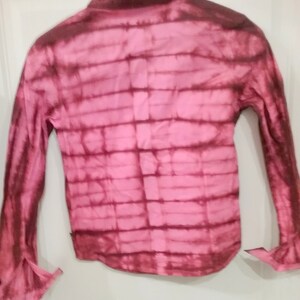 Puede incluir: Una camisa de manga larga con botones y un estampado tie-dye rosa y marrón.