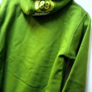 May include: Green hooded sweatshirt with a yellow embroidered logo that says "89" and "SO AND SO"