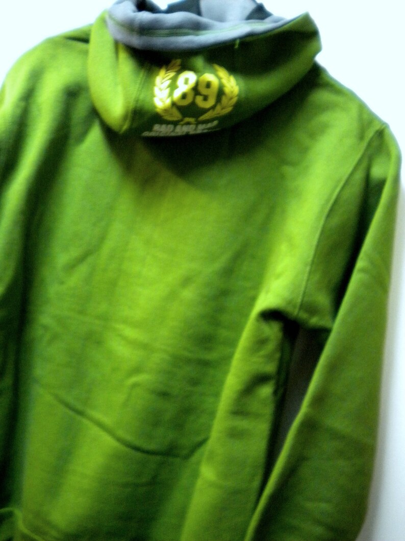 May include: Green hooded sweatshirt with a yellow embroidered logo that says "89" and "SO AND SO"