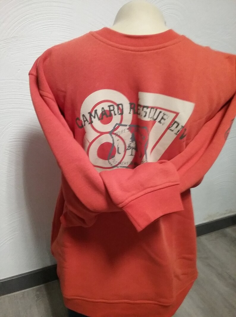 May include: Orange sweatshirt with a white graphic on the back that says "Camard Rescue Div" with a red circle and the number 87 inside.