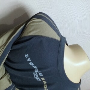 May include: A long-sleeved shirt with a dark blue body and olive green sleeves. The sleeves have a white stripe down the side. The shirt has a graphic print on the front that says "BADBOYS" and "2YOYO's".