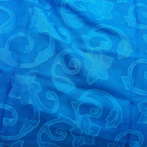 Peut inclure: Un tissu bleu avec un motif floral en relief blanc.