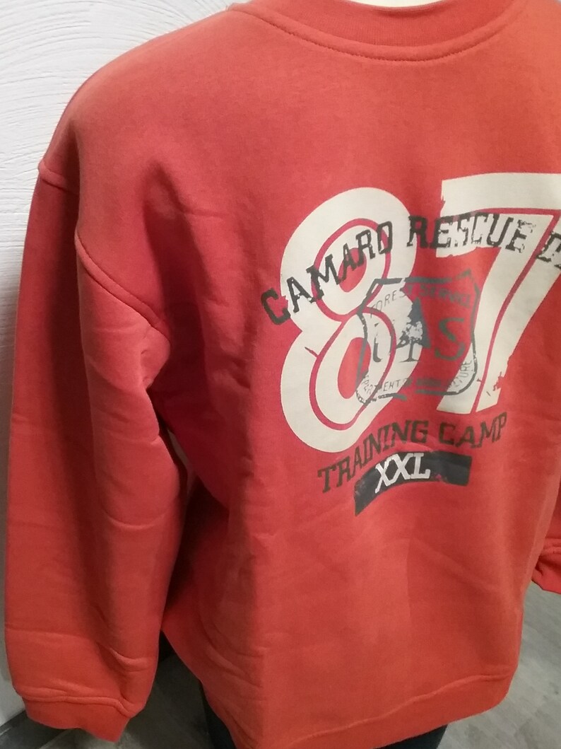 May include: Red sweatshirt with a white graphic print of "Camaro Rescue 87" with a smaller graphic of a tree and the text "Training Camp XXL".