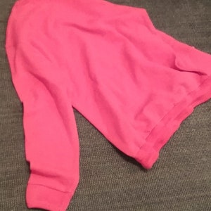 May include: A bright pink sweatshirt with long sleeves.