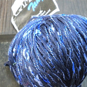 Puede incluir: Un ovillo de lana azul y blanco con una etiqueta que dice "Camelot Yarn".