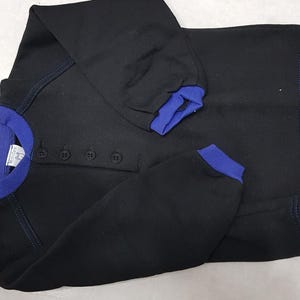 May include: Black long-sleeved sweatshirt with a blue trim around the neck and cuffs. The sweatshirt has four buttons down the front.