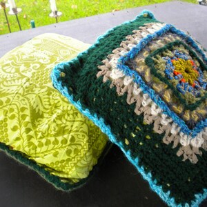 Peut inclure: Deux coussins décoratifs, l'un avec un motif floral vert et blanc, l'autre avec un design crocheté vert orné d'un motif géométrique coloré au centre.