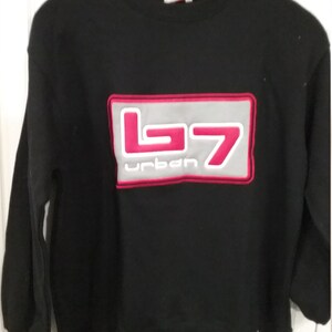 Può includere: Felpa nera con un logo rosso e bianco che dice "b7 urban" in un riquadro grigio.