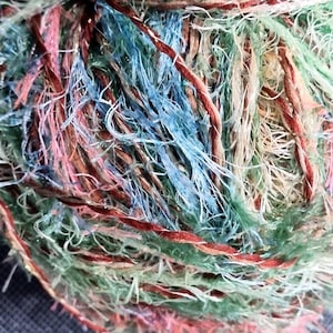 Puede incluir: Una taza de cerámica blanca con asa negra y el texto "But First, Coffee" en negrita negra. La taza se encuentra sobre un fondo borroso, sugiriendo un ambiente acogedor.