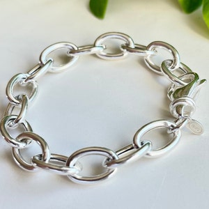 Pode incluir: Um bracelete de corrente de prata com elos ovais. O bracelete tem um fecho de lagosta.