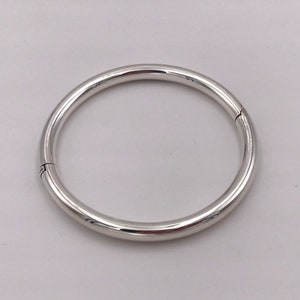 May include: A silver bangle bracelet with a hinged opening.