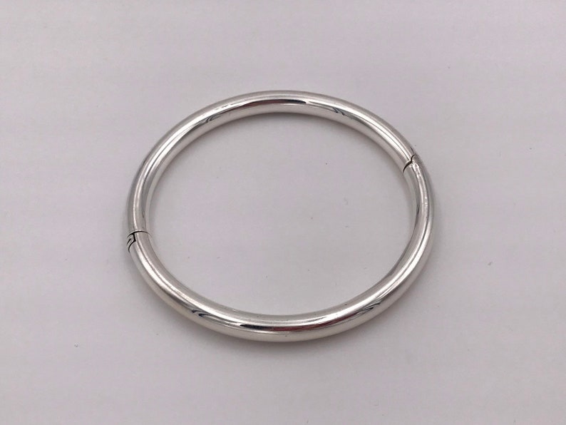 May include: A silver bangle bracelet with a hinged opening.