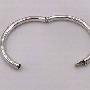 May include: A silver bangle bracelet with a hinged opening.