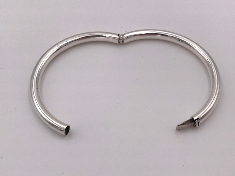May include: A silver bangle bracelet with a hinged opening.