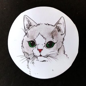 May include: A close-up of a white cat with green eyes and a red nose. The cat is looking directly at the viewer. The image is in a circular frame with the text "ST2-007" above it.