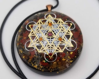 May include: A gold-toned metal pendant with a geometric design, set in a clear resin with red, orange, and gold flecks. The pendant is on a black cord.