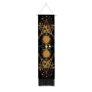 May include: Black tapestry with gold geometric patterns, including a butterfly, circles, and stars. The tapestry has a fringe at the bottom.