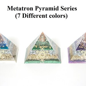 May include: Three Metatron Pyramid Series sculptures in blue, green, and purple. Each pyramid features a copper coil at the apex and a gold-colored geometric design on the base. The text "Metatron Pyramid Series (7 Different colors)" is above the pyramids.
