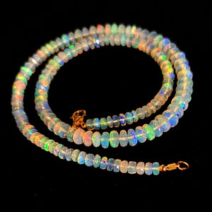 May include: A delicate necklace made of iridescent opal beads. The necklace is strung on a gold chain and features a simple clasp.